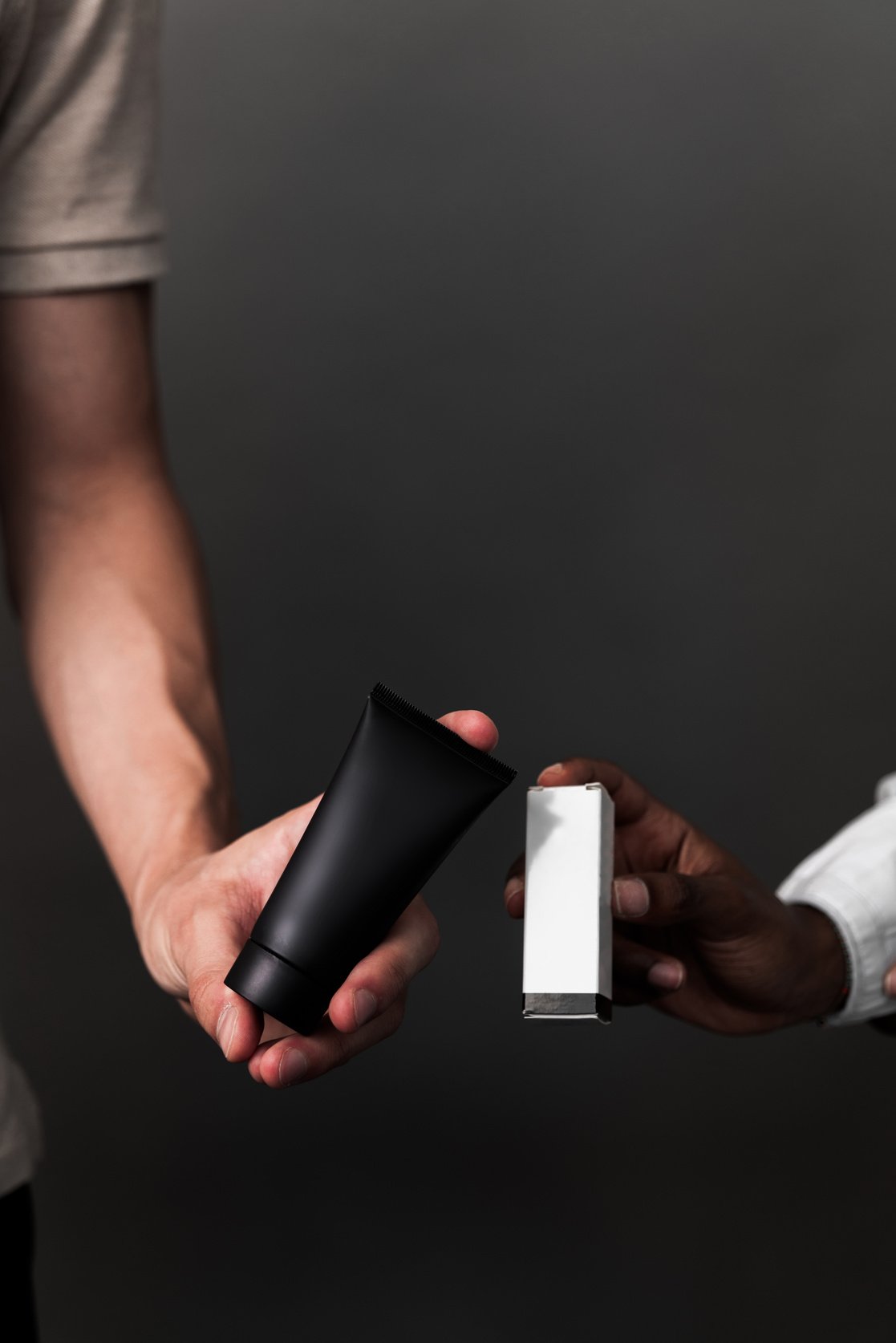 Two Person's Hands Holding Cosmetic Cream and Box